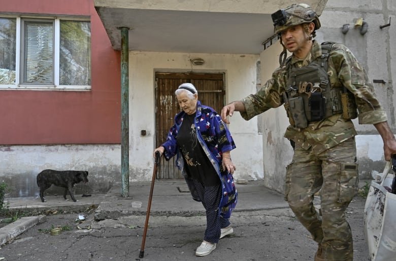 A police officer assists a civilian woman during an evacuation from outskirts of the Kurakhove town, amid Russia's attack on Ukraine, in Donetsk region, Ukraine September 16, 2024