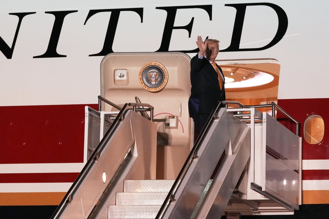 A man waves from the top of the staircase leading to an airplane.