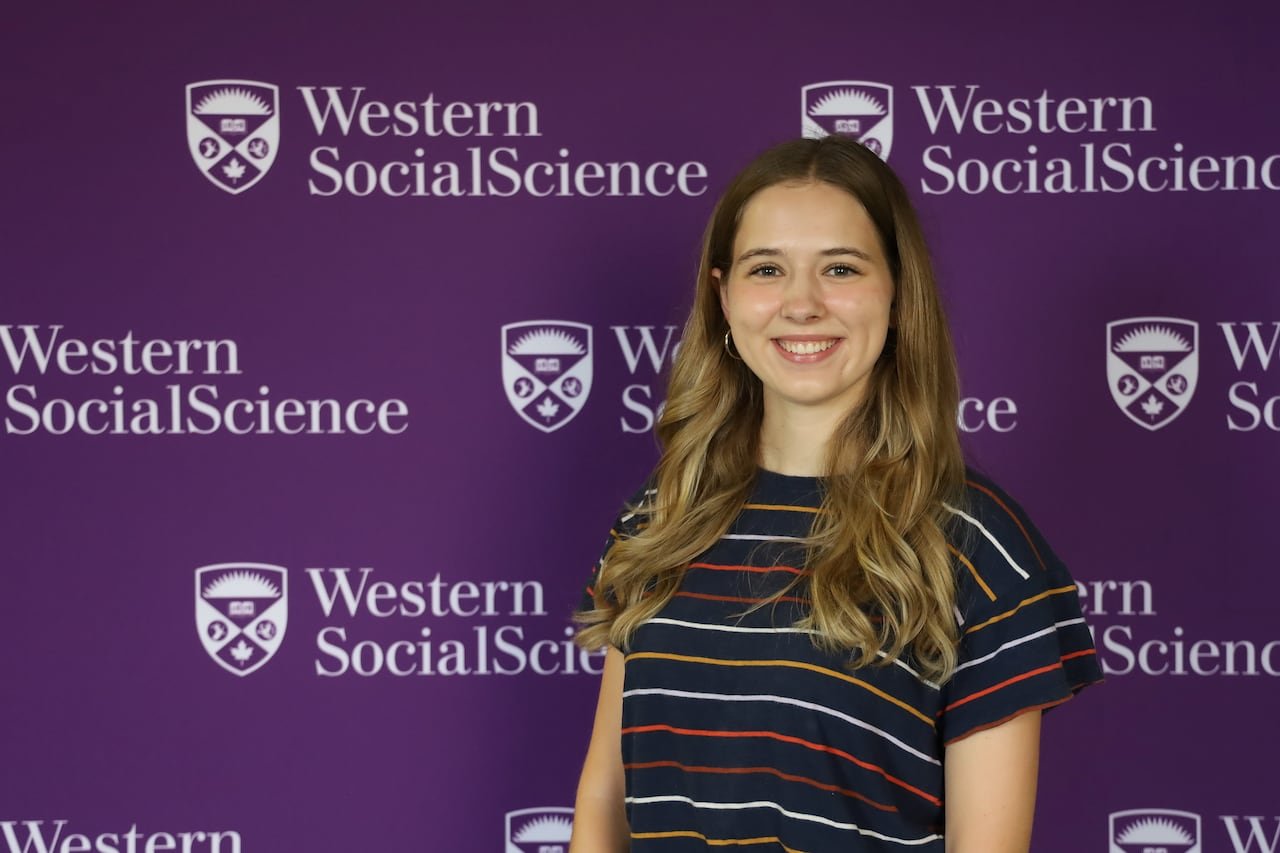 student stands in front of a Western University decal wall