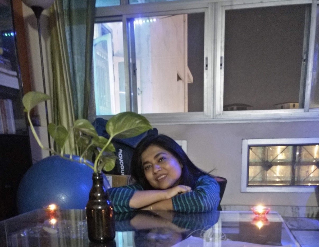 default-439 Large windows can be seen in the background as a woman sits, her arms resting on a clear kitchen table.