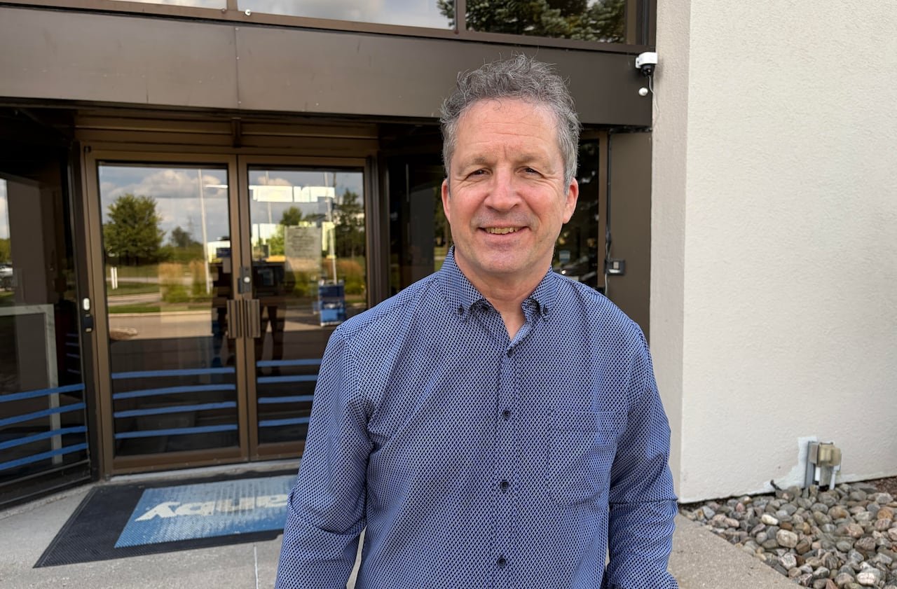 default-179 a man in a blue collared shirt stands in front of the glass doors of a building
